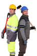 Tradesmen standing back to back and holding tools