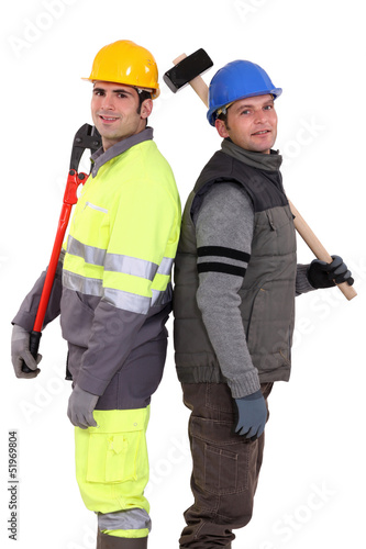 Photo: Tradesmen standing back to back and holding tools Tradesmen standing back to back and holding tools