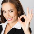 Happy business woman with okay gesture, over gray
