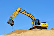 new yellow excavator working on sand dunes