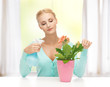 woman holding pot with flower and spray bottle