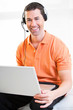 Happy business male on laptop with headset on smiling