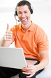 Happy business male on laptop with headset on smiling
