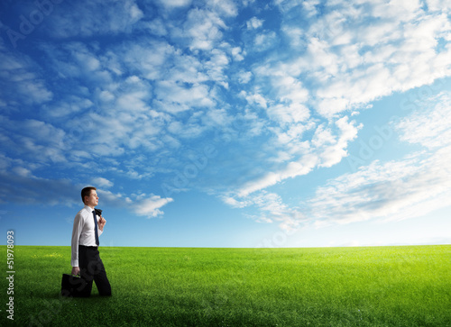Photo: young business man wolking at the field of grass young business man wolking at the field of grass