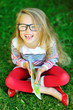 Adorable little girl in glasses holding book and laughing - outd