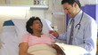 Doctor Talking To Senior Female Patient In Hospital Bed