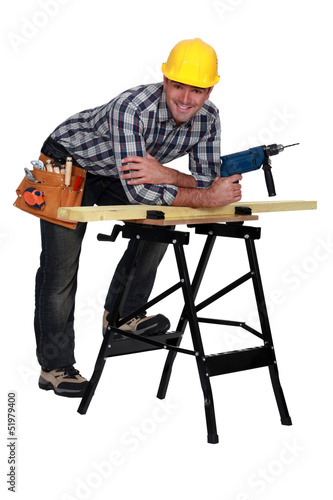 Photo: Carpenter with drill casually leaning on work bench Carpenter with drill casually leaning on work bench