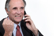 Photo: mature businessman on the phone clenching his fist mature businessman on the phone clenching his fist
