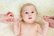 baby girl holding parental hands lying on fur bed