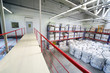 Warehouse with heap of big white sacks on floor and shelves