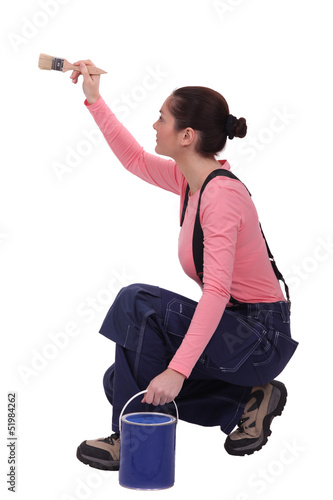 Photo: Crouched woman painting wall Crouched woman painting wall