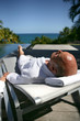 Old man laying on poolside sun lounger