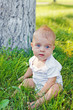 Foto: Smiling little boy sitting in fresh grass Smiling little boy sitting in fresh grass