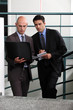 Photo: Businessmen comparing notes in stairwell Businessmen comparing notes in stairwell