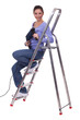 Woman sitting on stairs with drill