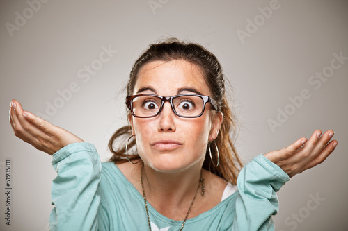 Photo: Shrugging woman in doubt doing shrug showing open palms. Shrugging woman in doubt doing shrug showing open palms.