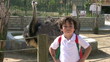 Little boy at the zoo with ostrich smiling to the camera