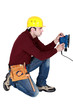 Man kneeling with power sander