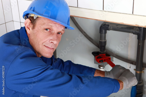Photo: Plumber using a wrench on a water pipe Plumber using a wrench on a water pipe