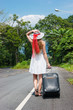 young girl walking down the road with a suitcase