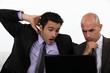 Photo: Two shocked office workers holding laptop Two shocked office workers holding laptop