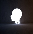 Man walking into a head-shaped opening in a wall