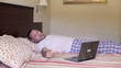 Man waking up and checking laptop computer