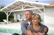 Foto: Couple sat in the garden by swimming pool Couple sat in the garden by swimming pool