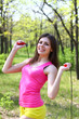 Smiling young woman with a skipping rope in a summer park