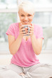 Smiling woman with mug sitting at home while smiling