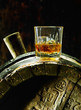 whiskey in a glass with ice on an oak barrel