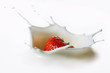 Red strawberry fruits falling into the milk