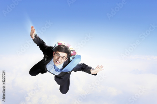 Photo: Young businessman flying with parachute on back Young businessman flying with parachute on back