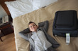 Smiling business woman laying on bed in hotel room