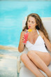 Young woman laying on chaise-longue and drinking cocktail