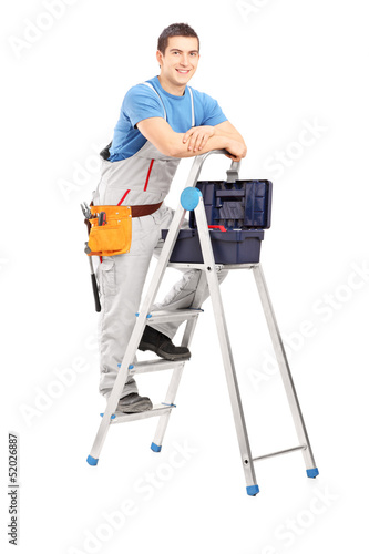 Photo: Full length portrait of a handy man posing on a ladder Full length portrait of a handy man posing on a ladder