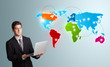 Photo: young man holding a laptop and presenting colorful world map young man holding a laptop and presenting colorful world map