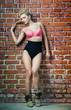 girl in swimsuit posing provocatively in front of a brick wall
