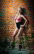 girl in swimsuit posing provocatively in front of a brick wall
