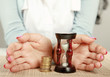 Female hand's with hourglass and coin