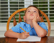 Thoughtful child doing his homework at kitchen table