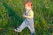 smile child in the  jeans coverall walk on the grass