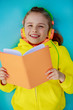 Foto: Young girl in headphones reading a book Young girl in headphones reading a book