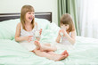 Photo: Two little girls drinking milk from glasses on bed Two little girls drinking milk from glasses on bed