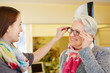 Optician advising senior woman buying glasses