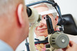 Senior woman behind slit lamp at optician