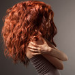 Beautiful woman with curly hairstyle against gray background