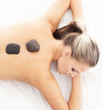 Young attractive woman getting hot stone treatment over white ba