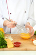 Female hands blending eggs in glass bowl