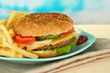 Tasty cheeseburger with fried potatoes, on bright background